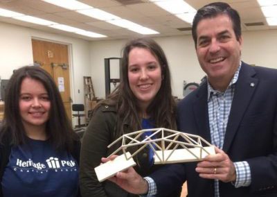 Dr. Paul Keefer holding a model bridge with students