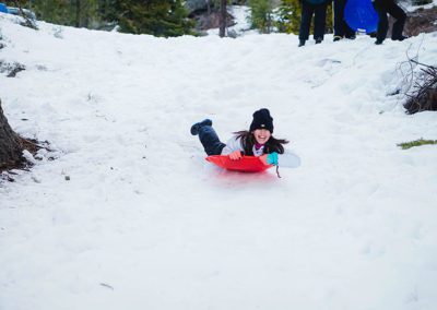 Sutter Peak school kid sledding down a snow hill