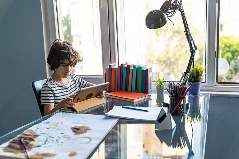 Kid studying at a desk near a window